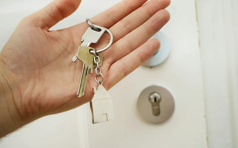 Hand holding the keys to a home next to a door